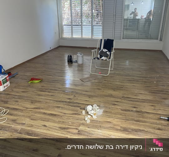 סלון בדירה ריקה עם רצפת פרקט במהלך עבודת ניקיון